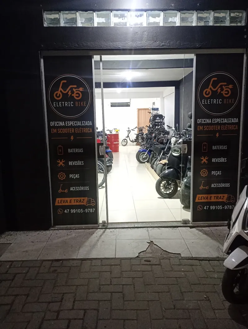 Fachada da Eletric Bike à noite, com scooters na loja